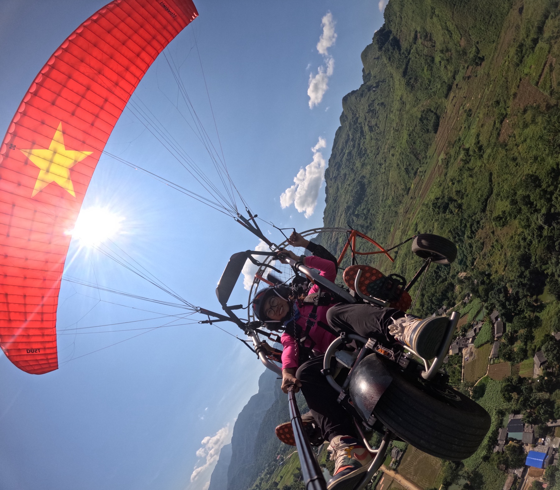 Paramoteur biplace en virage au-dessus des champs de la vallée de la Miện, Quản Bạ