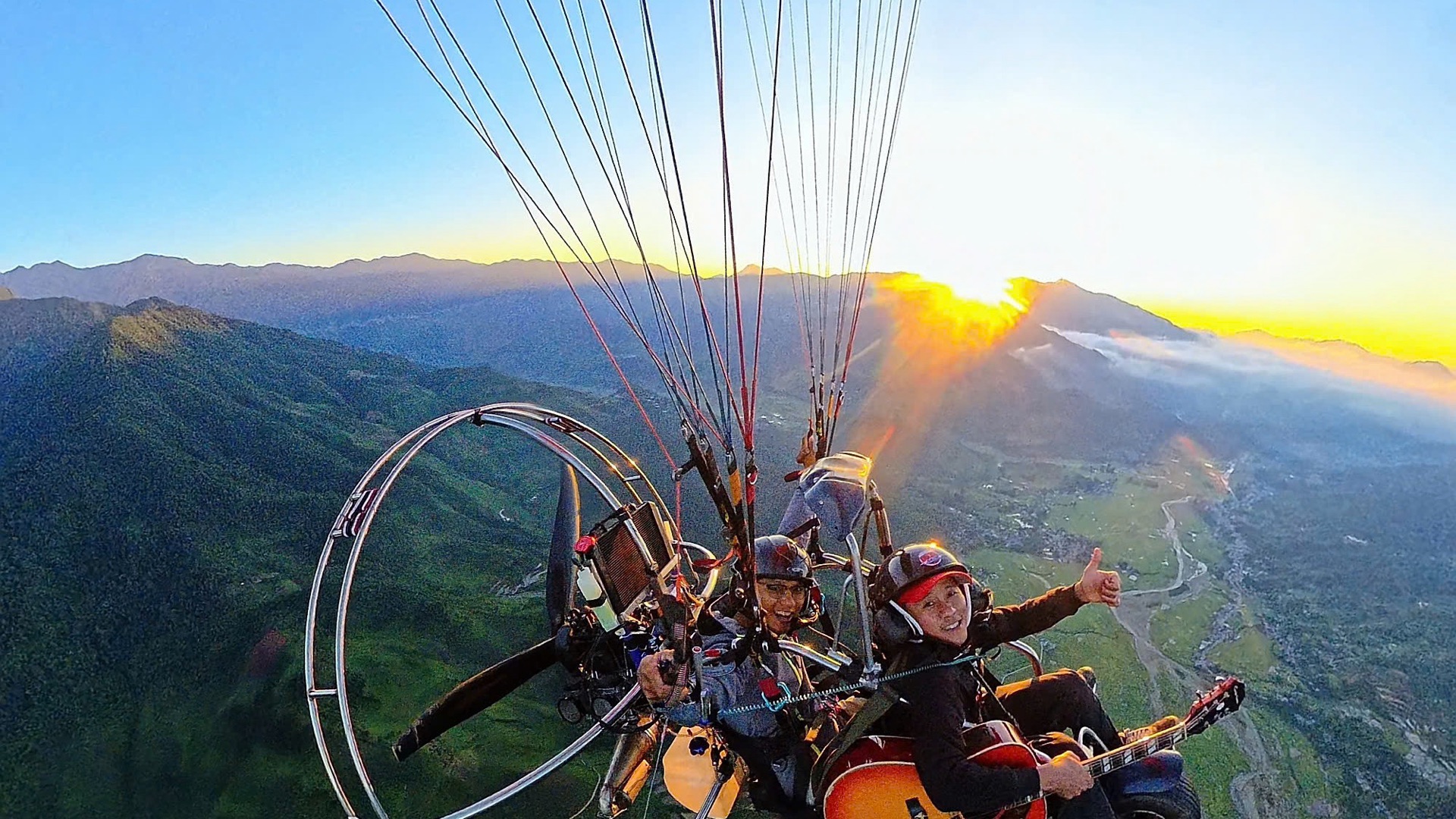 Paramotor đôi ôm đàn guitar trước mặt trời lặn